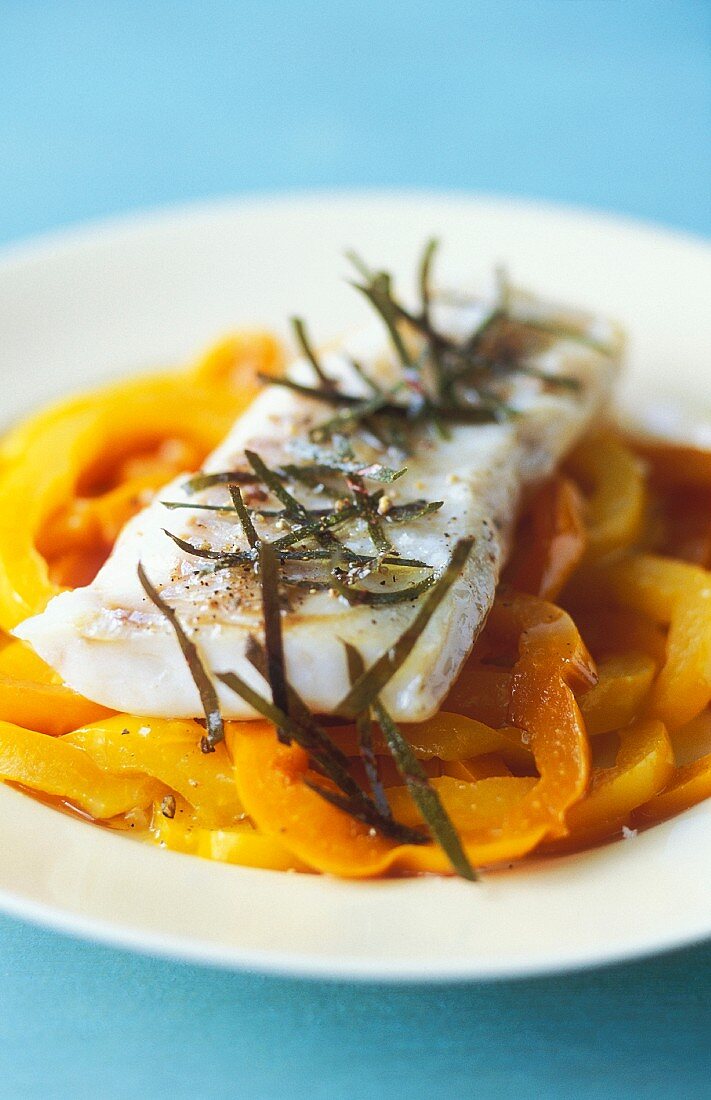 Cod fillet with bay leaves on a yellow pepper medley