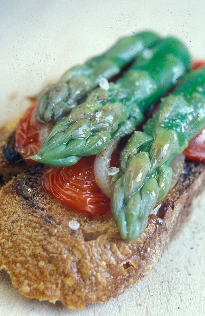 Grilled bread with green asparagus, tomatoes, onions and olive oil