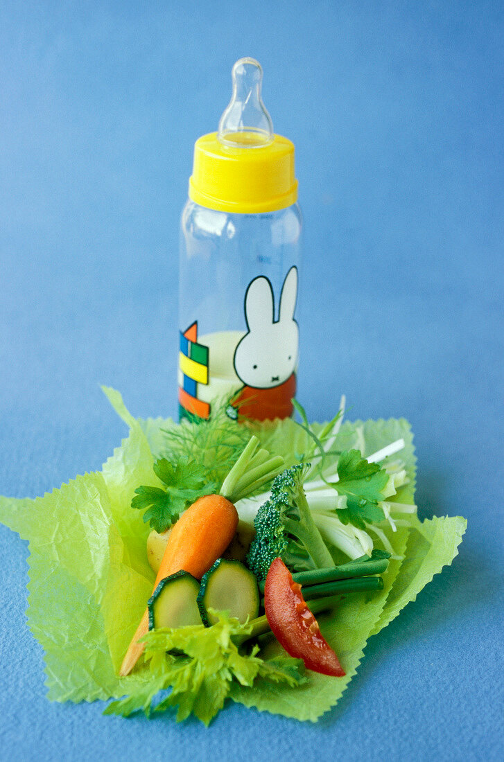 Gemüsestückchen auf Papier und Babyflasche