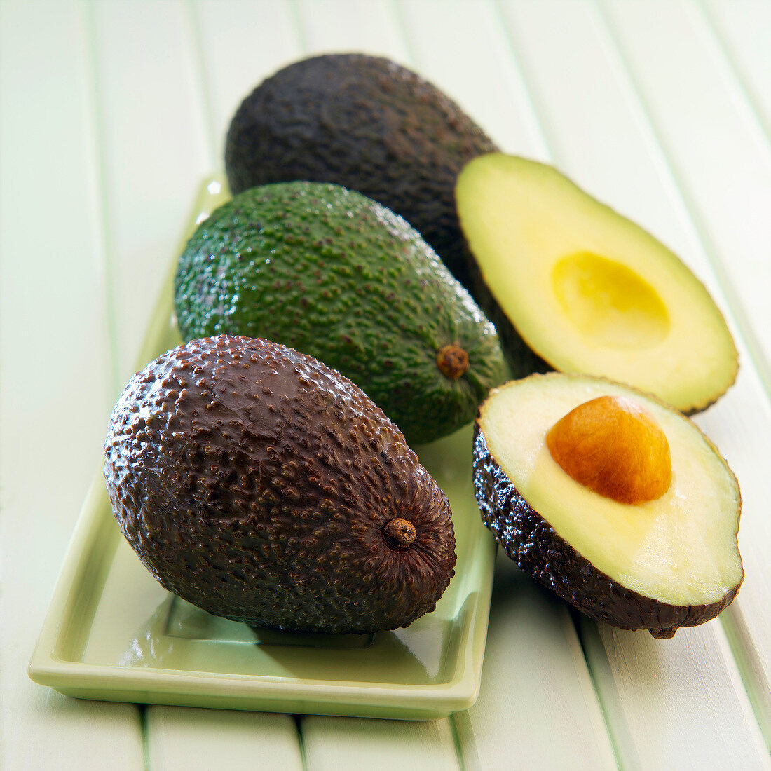 Vier Avocados, eine halbiert