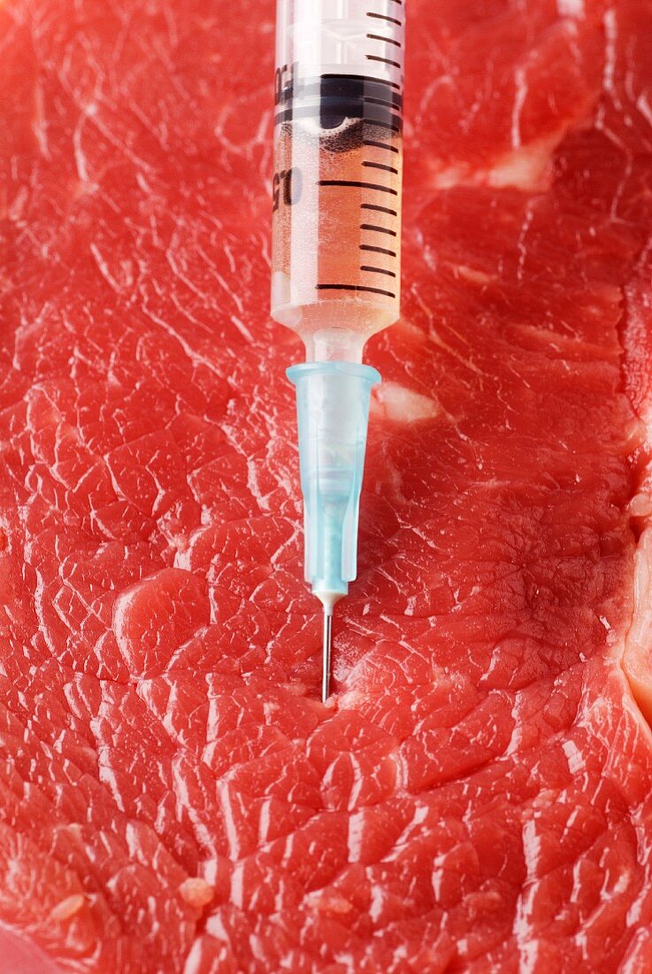 Pricking red meat with a syringe full of hormones