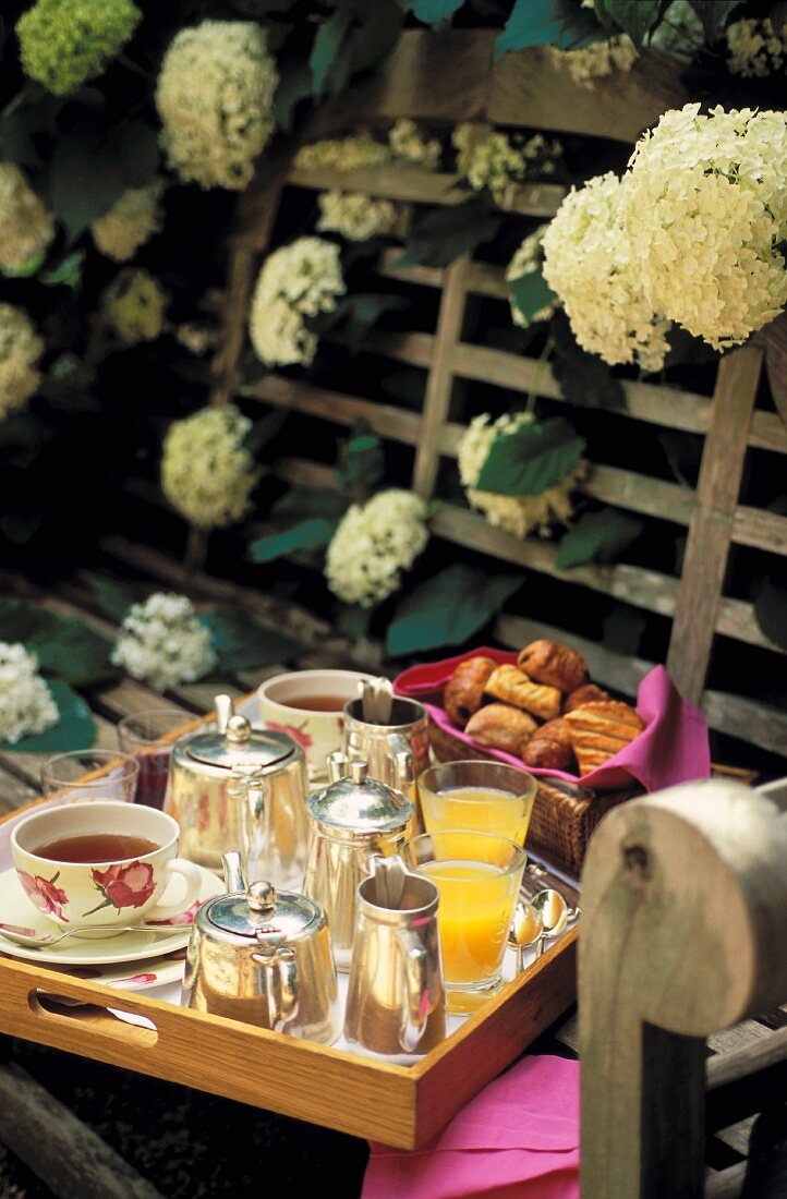 A breakfast tray on a wooden bench with white flowers