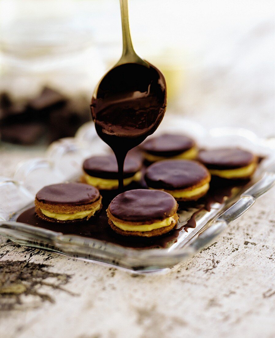 Cookies being covered with chocolate glaze