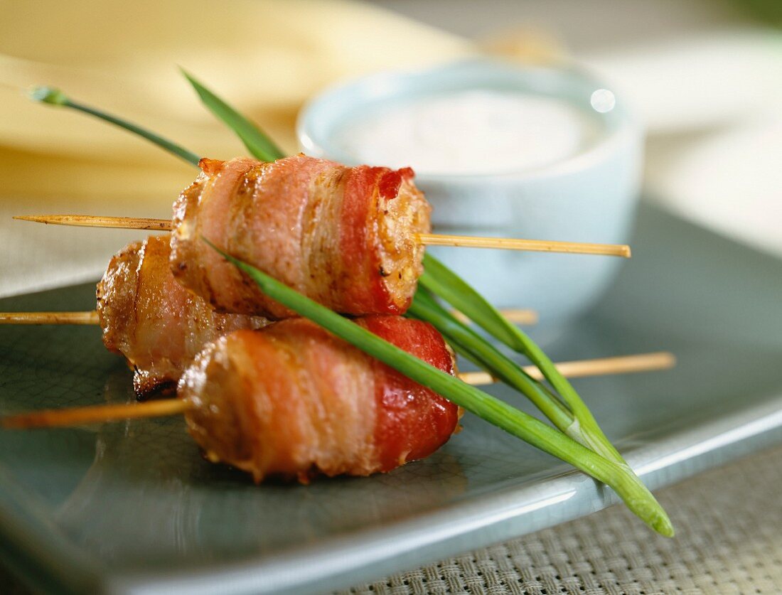 Sausages wrapped in bacon on sticks
