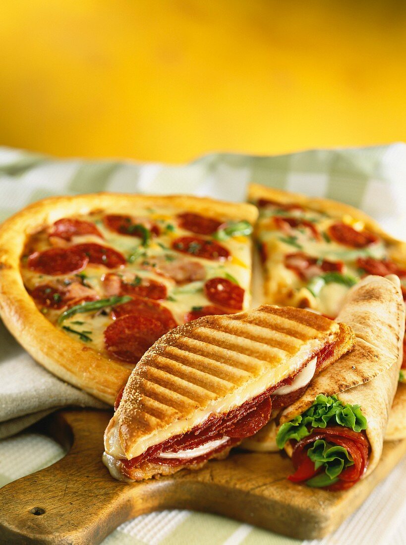 A toasted sandwich, rolled pita bread and a chorizo pizza