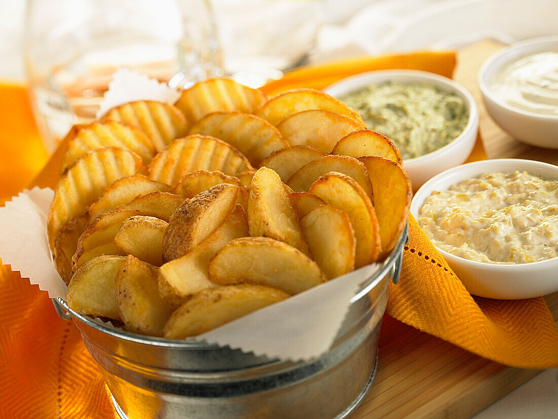 Bucket full of assorted fried potatoes with a selection of dips