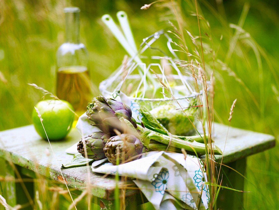 Salat, Artischocken und Apfel auf einem Gartentisch