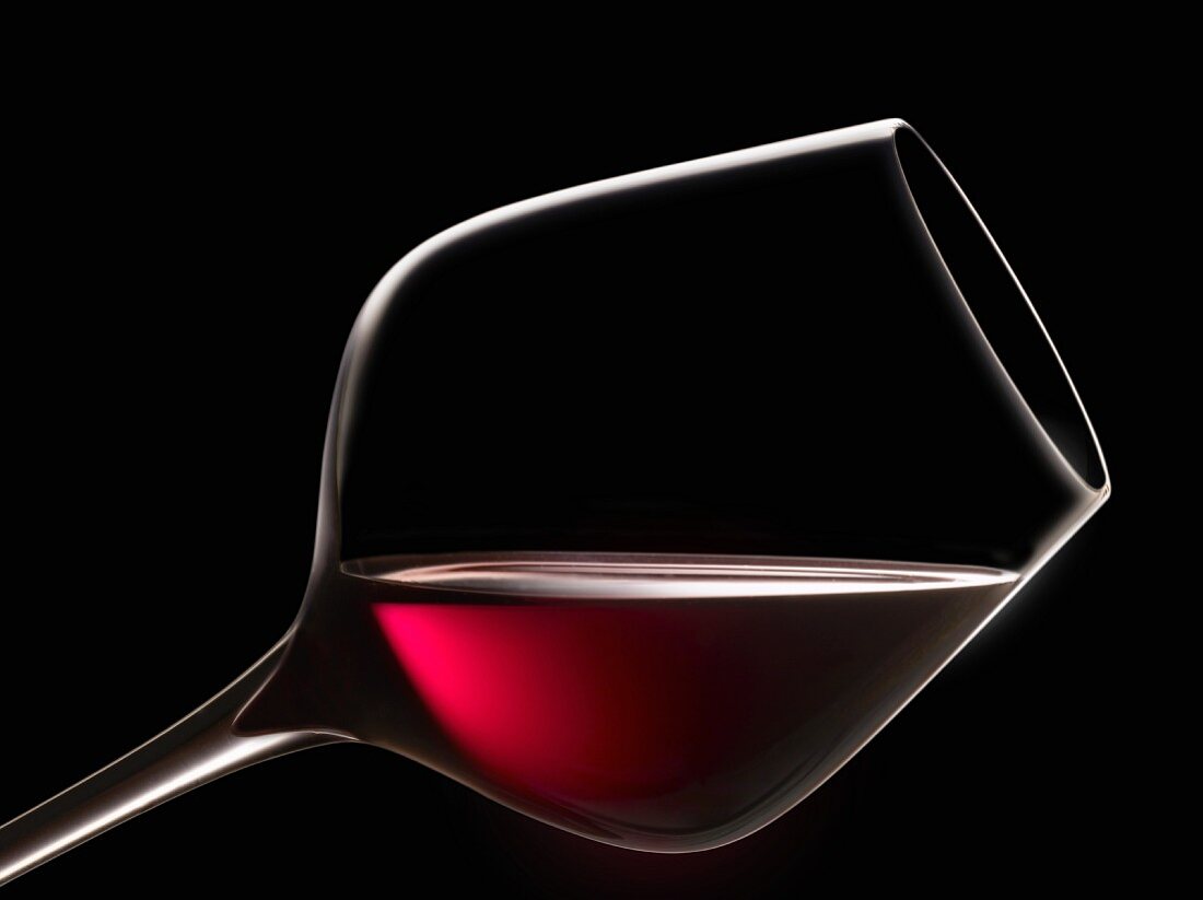 Schräg haltendes Glas Rotwein zur Degustation