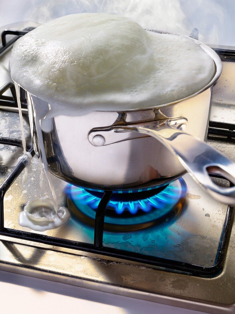 Milk boiling over the top of a saucepan