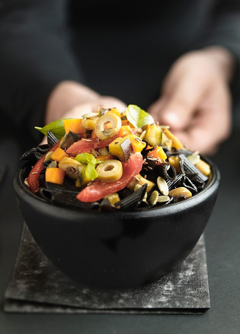 Pasta salad with squid penne, olives, tomatoes, aubergines and peppers