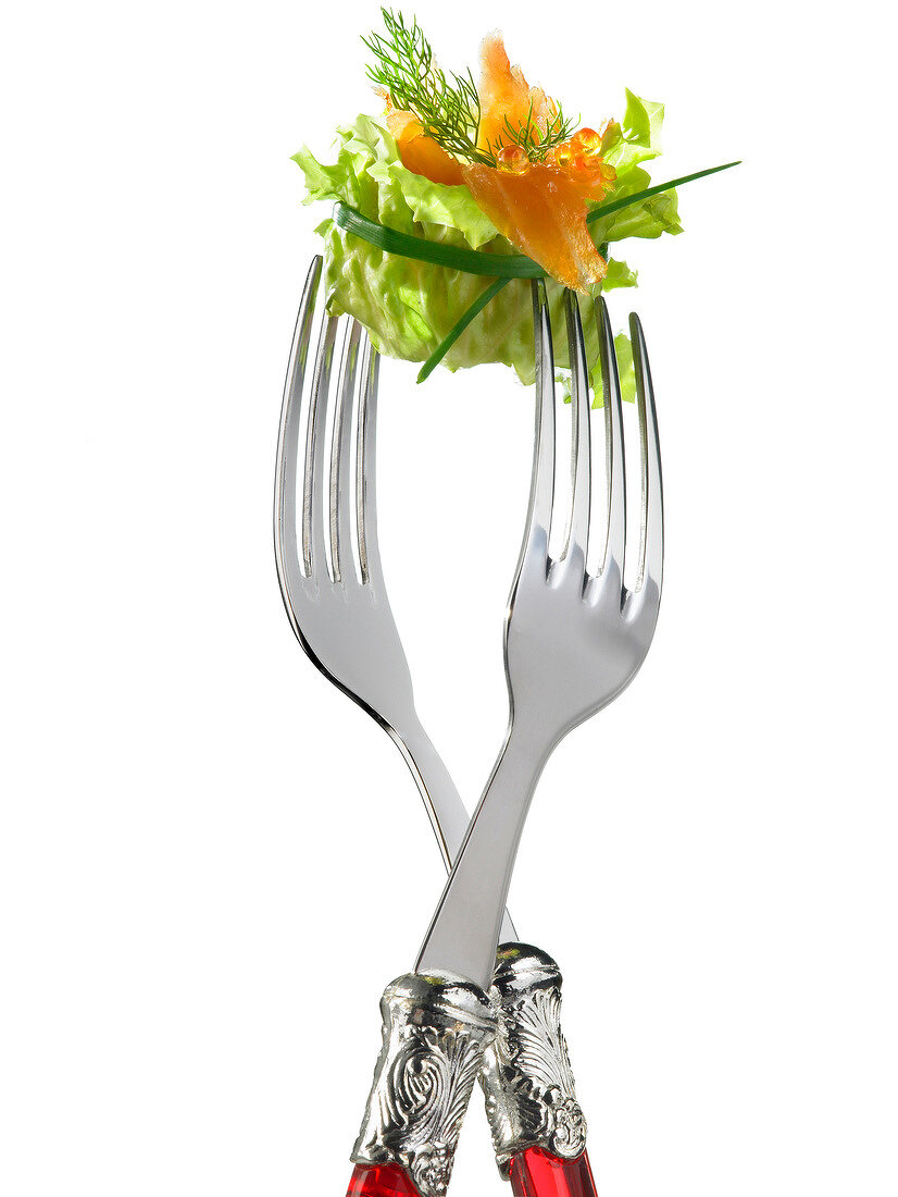 Zwei Gabeln halten Salatpäckchen mit Lachs