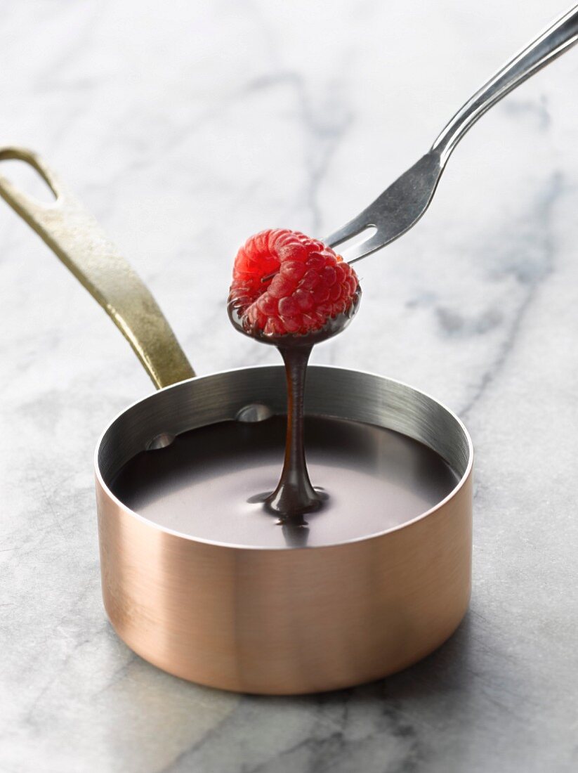 Dipping a raspberry into a saucepan of melted chocolate