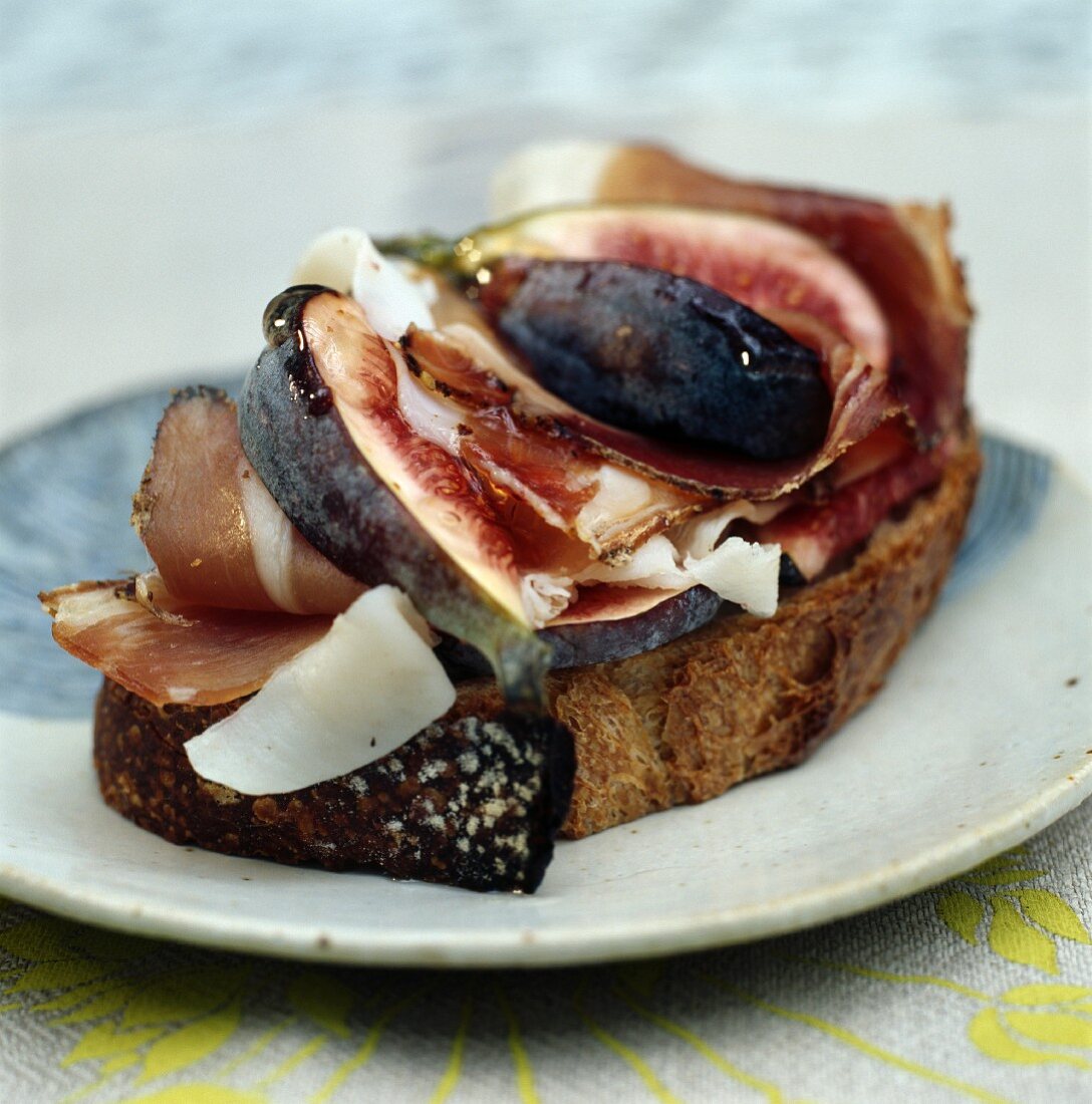 Dry-cured ham with figs and Parmesan cheese on a slice of grilled bread
