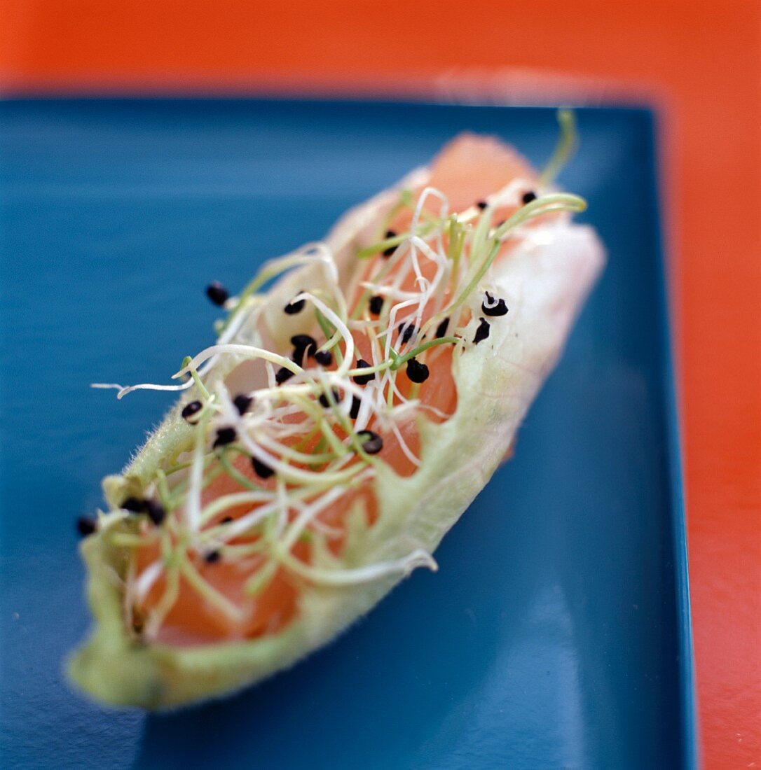 A chicory boat with salmon tatar and lentil sprouts