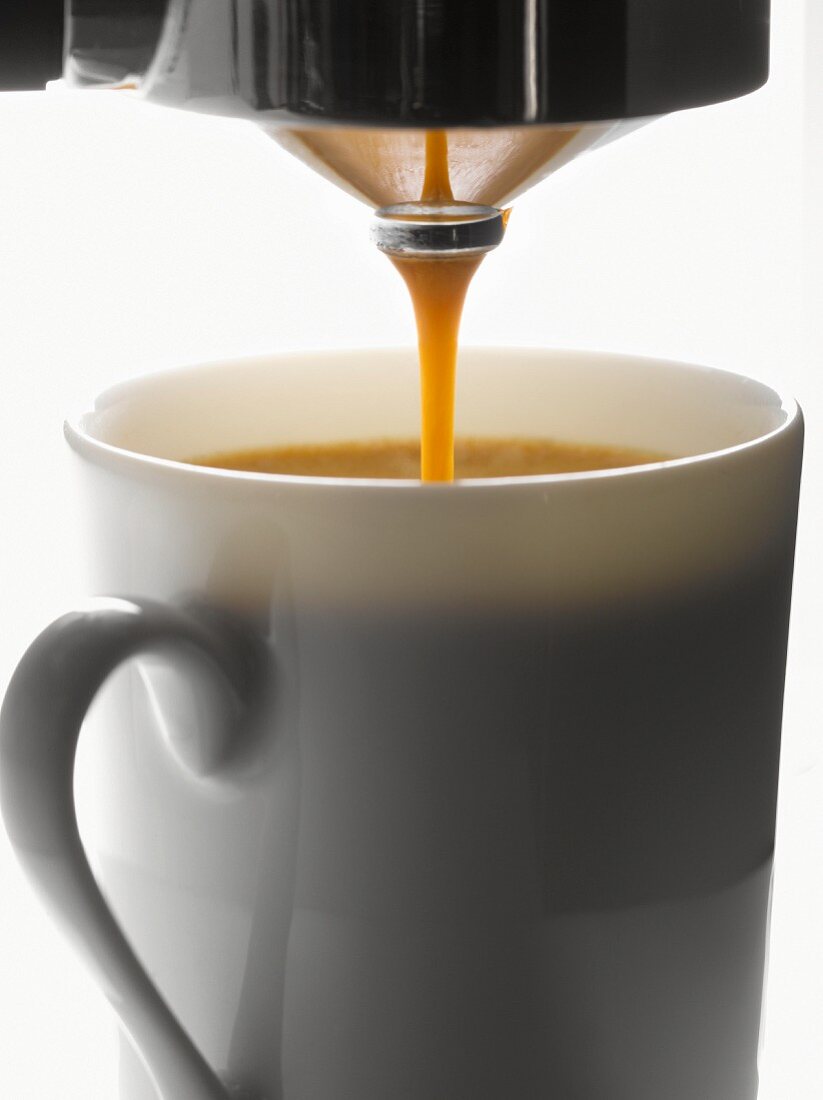 Kaffee läuft aus einer Kaffeemaschine in die Tasse