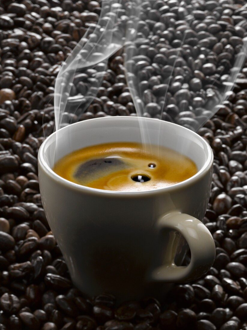 Dampfender schwarzer Kaffee in einer Tasse auf Kaffeebohnen