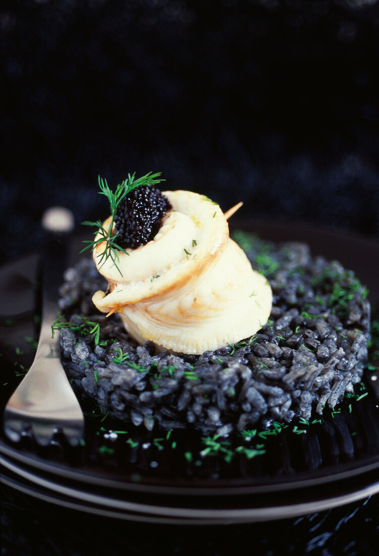 Seezungenröllchen mit Sevruga-Kaviar auf schwarzem Tintenfischrisotto