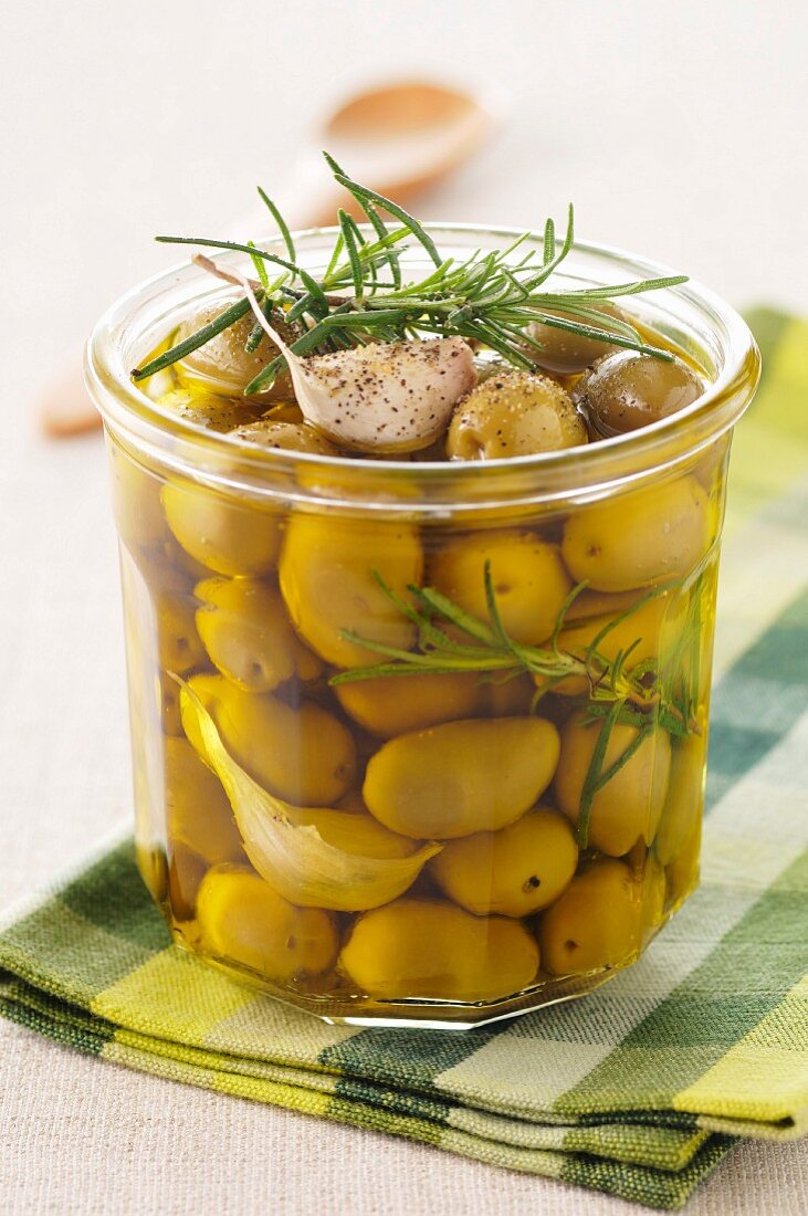 Jar of green olives marinated with garlic and rosemary