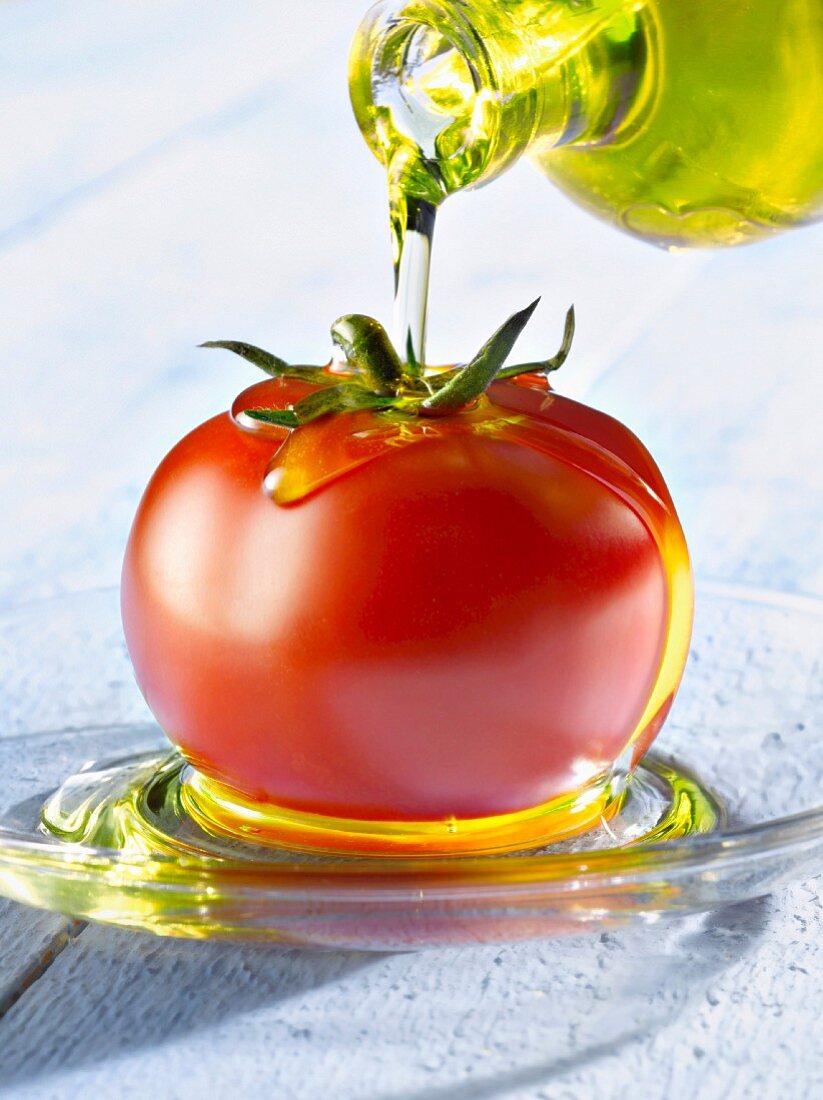 Pouring oil onto a whole tomato