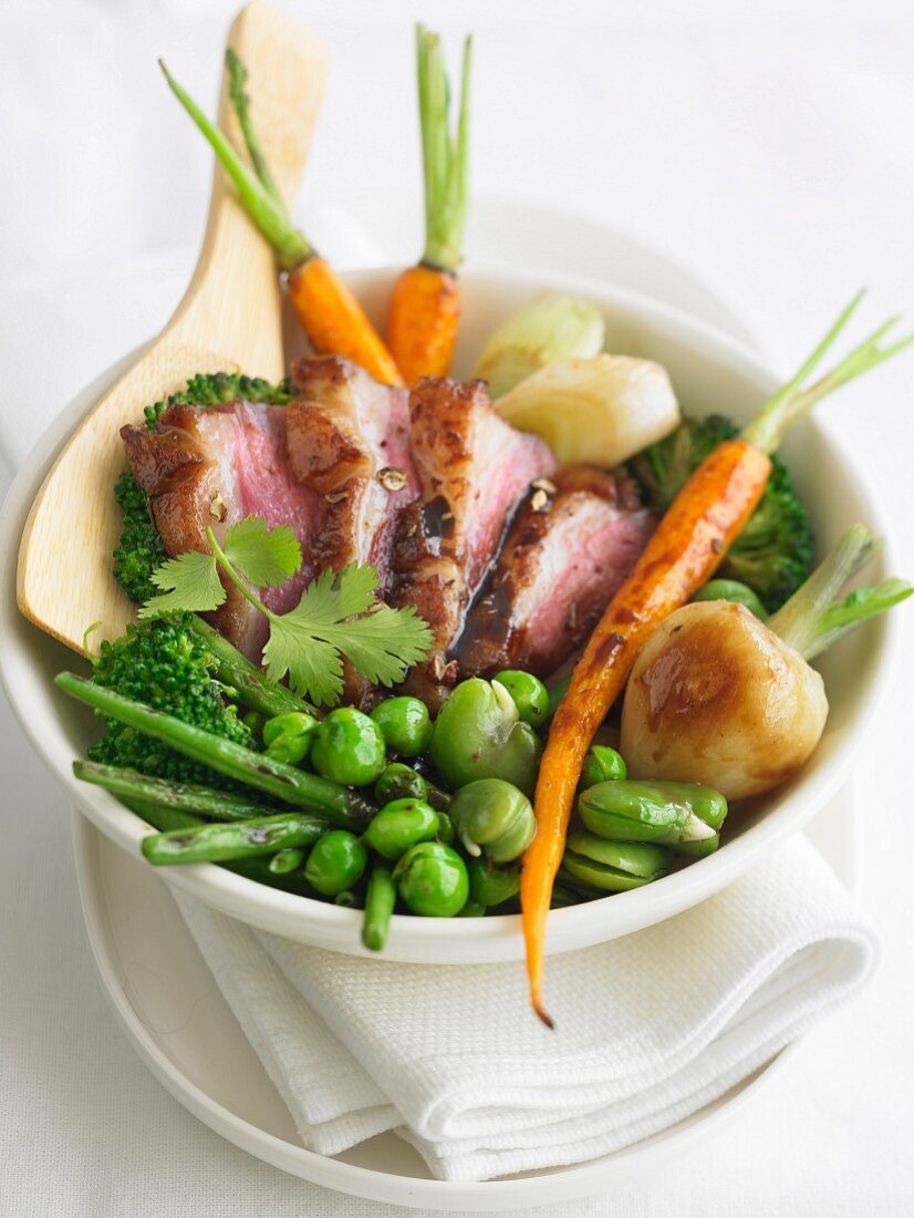 Young vegetables sauteed in a wok, sliced duck breast
