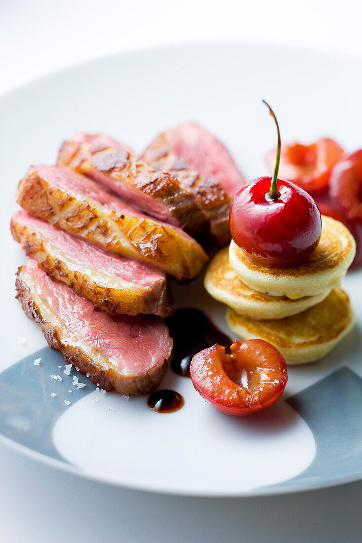 Sliced duck Magret with cherry sauce and mini blinis