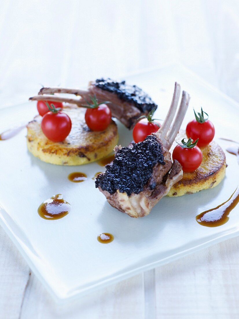Lamb chops coated with tapenade, polenta cakes and cherry tomatoes