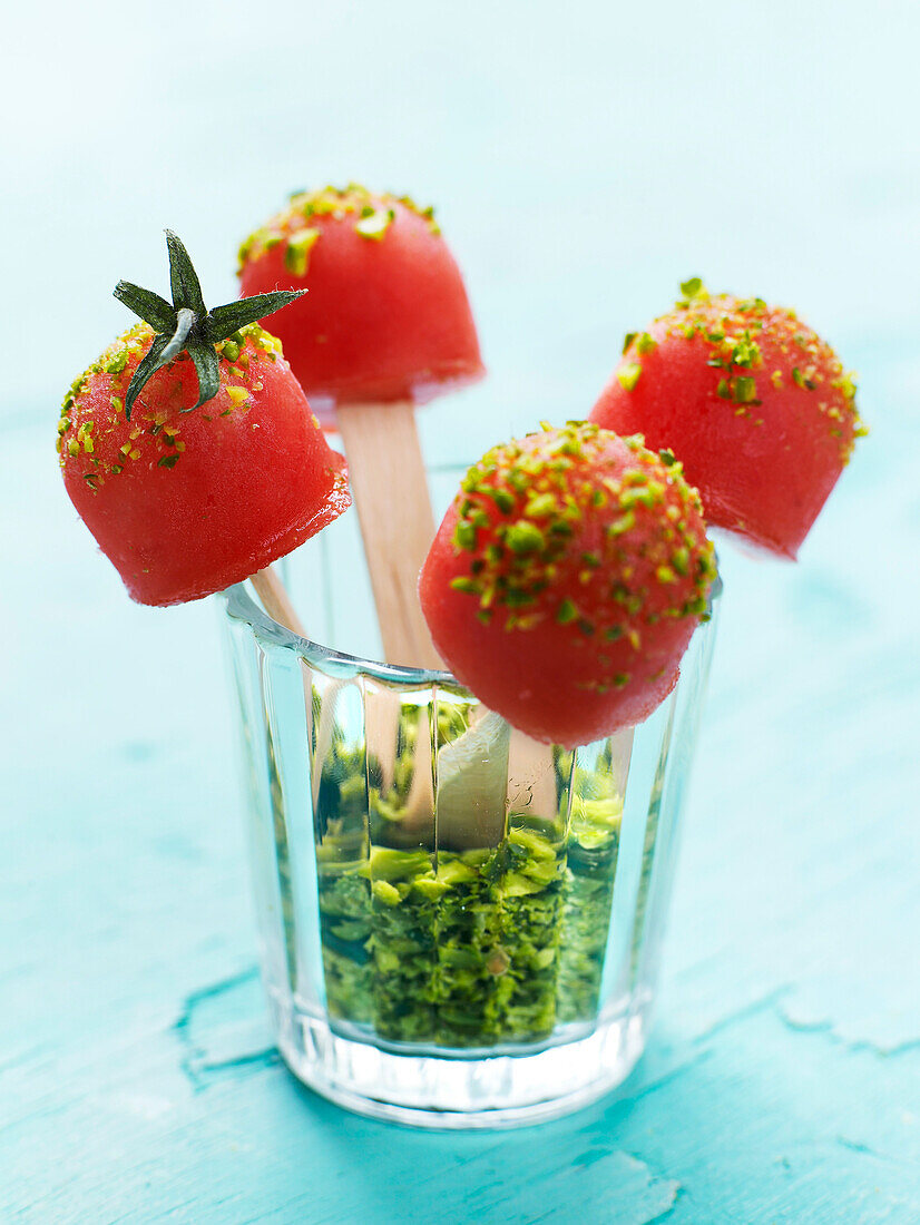 Tomato sorbet lollipops coated with crushed pistachios