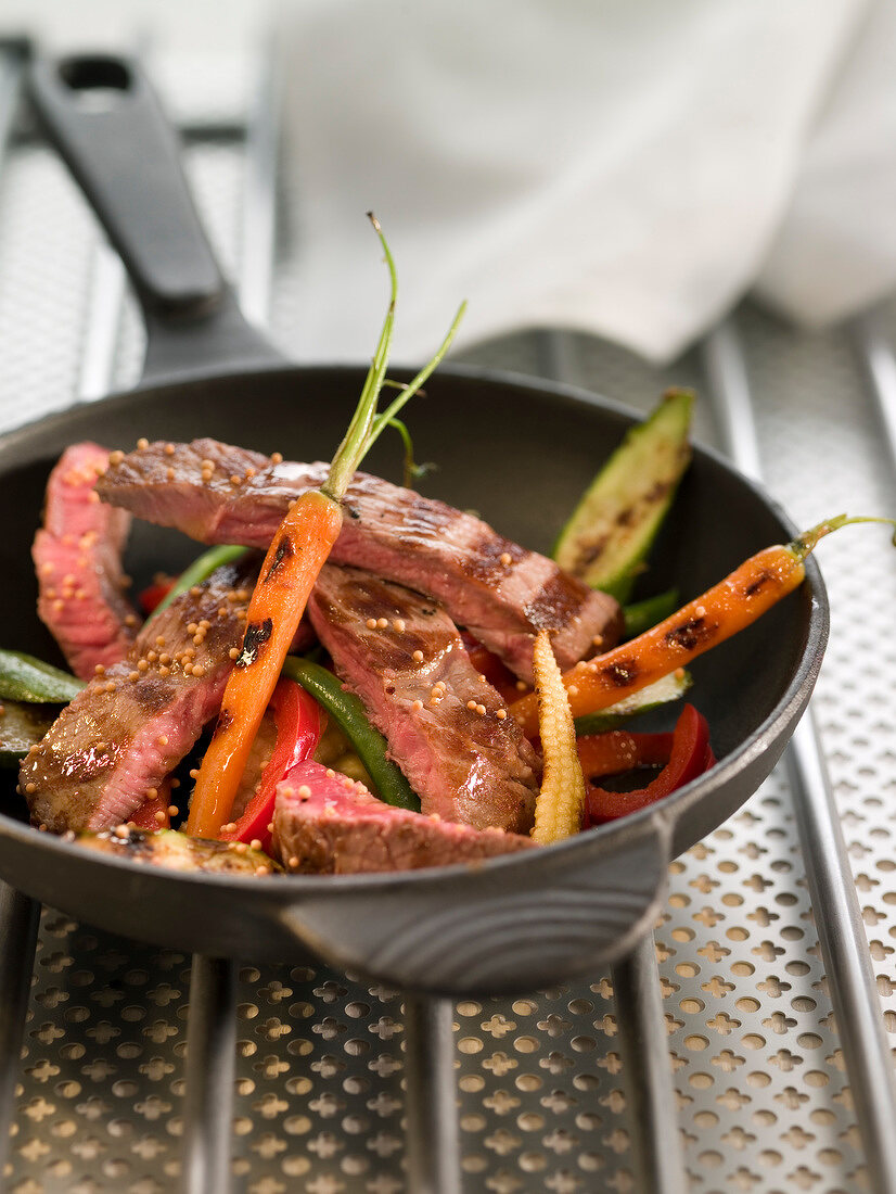 Sliced veal steak with young vegetables and mustard seeds