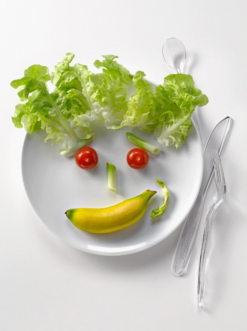Plate of vegetables and mini banana in the shape of a face