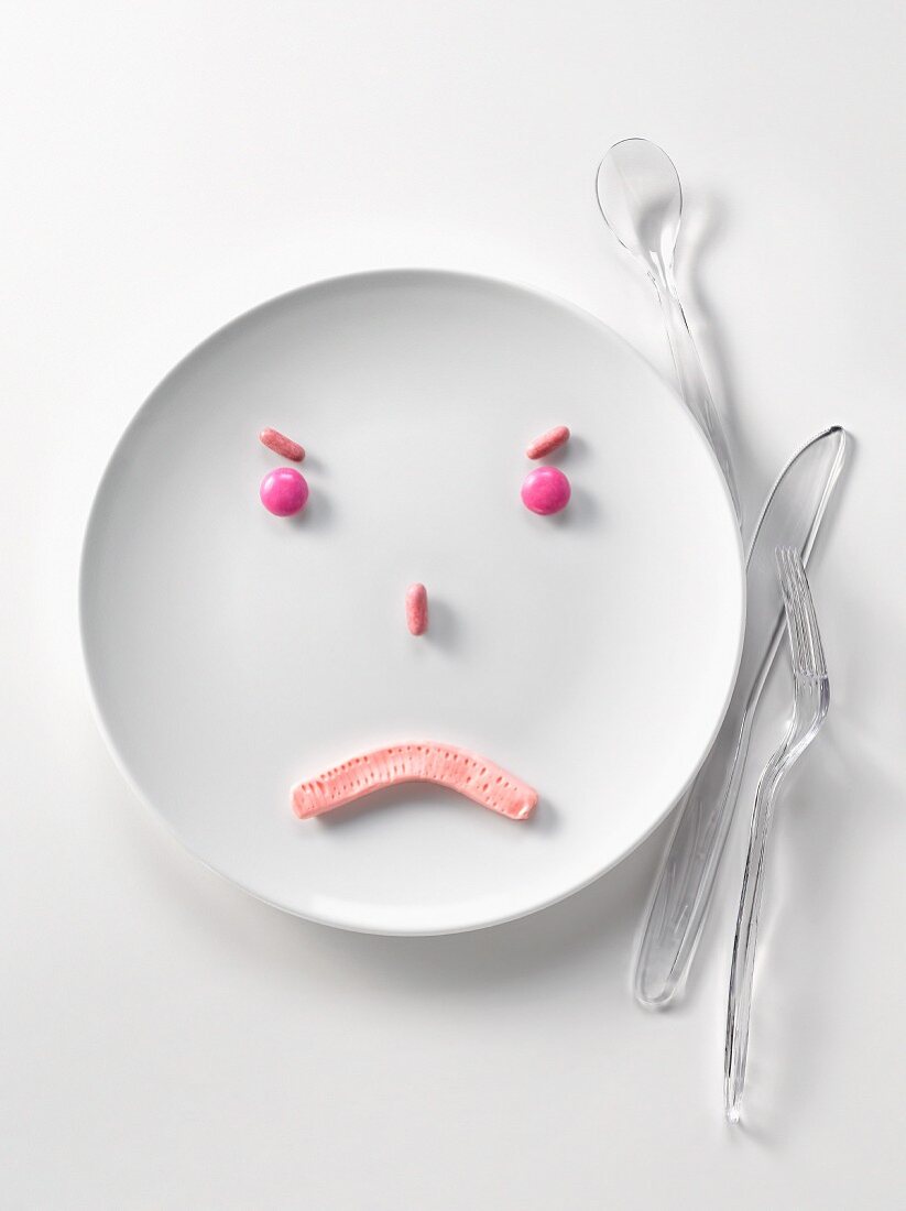 Plate of pink candies in the shape of a sad face