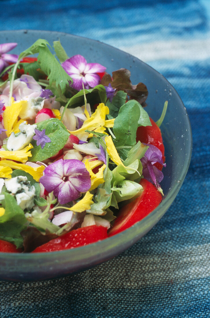 Sommerlicher Salat mit Tomaten, Gorgonzola und Blüten in einer Schale