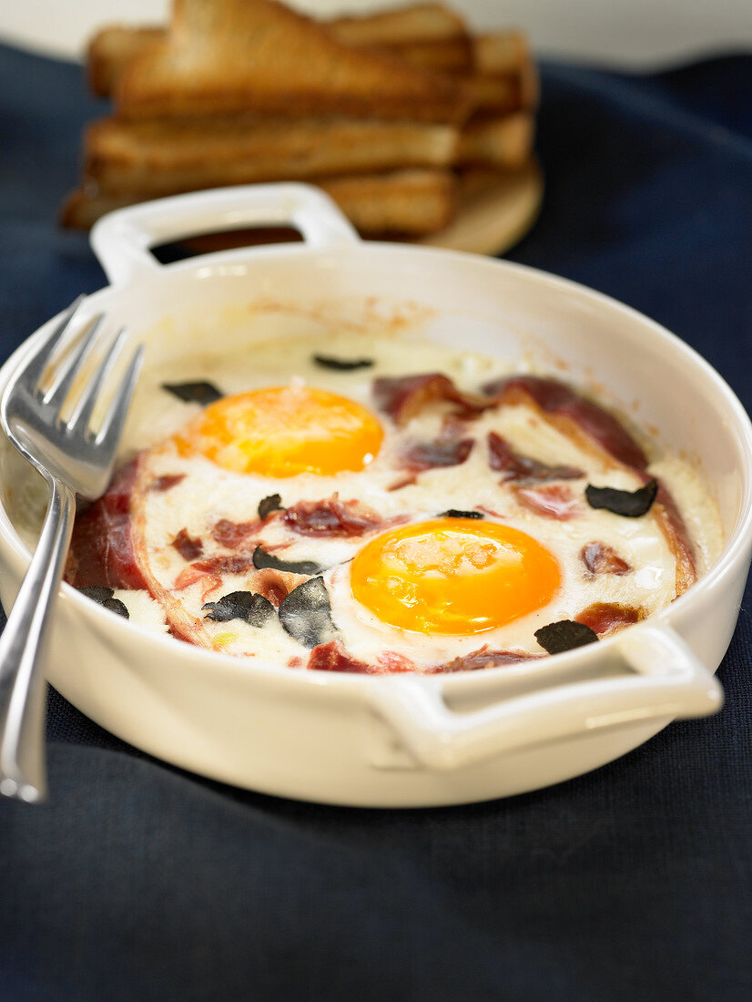 Baked eggs with cream, truffles and ham