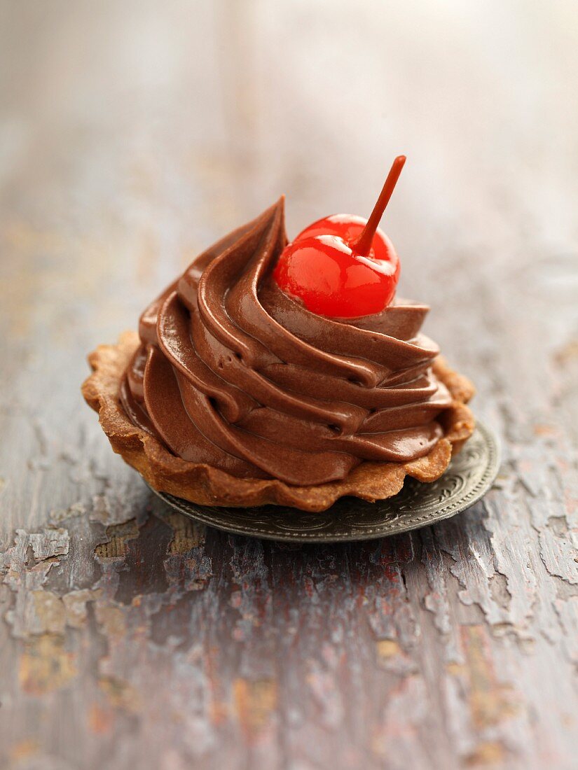 Chocolate ganache tartlet topped with a candied cherry