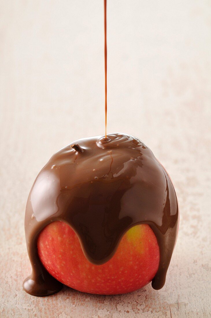 Einen Apfel mit flüssiger Schokoladenkuvertüre bedecken