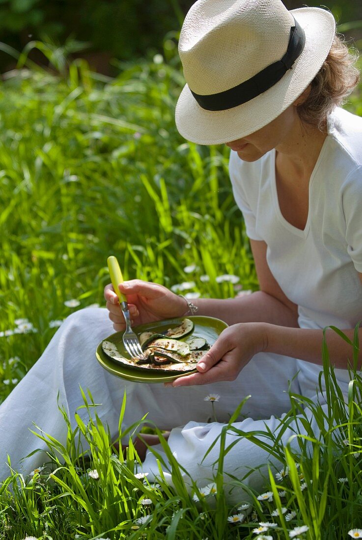 Person eating grilled zucchinis outdoors