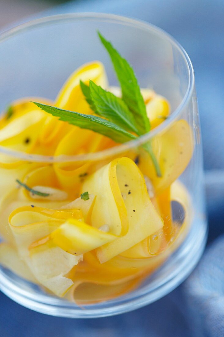 Gelbe Zucchinistreifen mit Pinienkernen und Minze