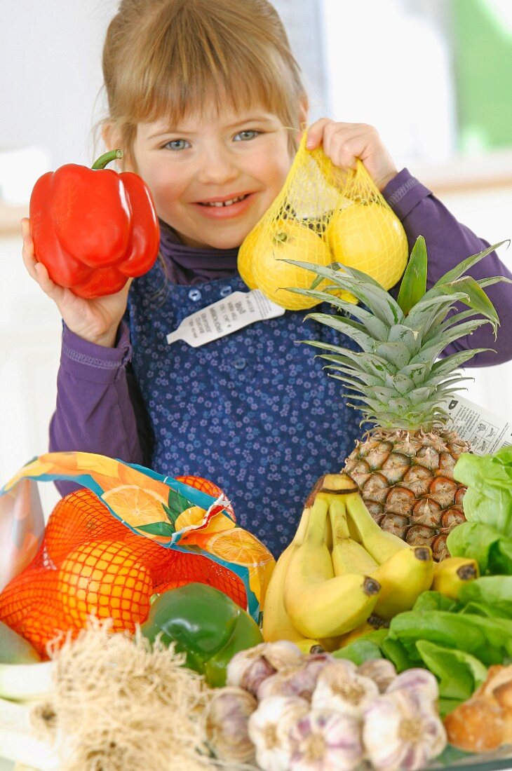 Young girl holding bags of fruit and vegetables