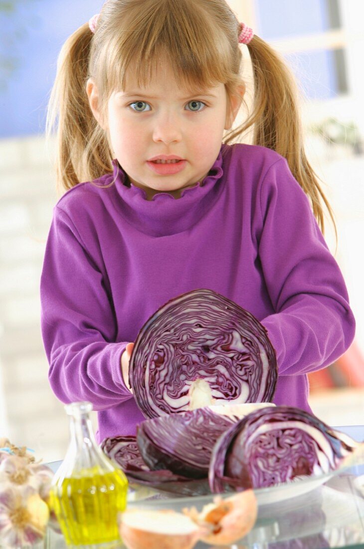 Kleines Mädchen schneidet Rotkohl