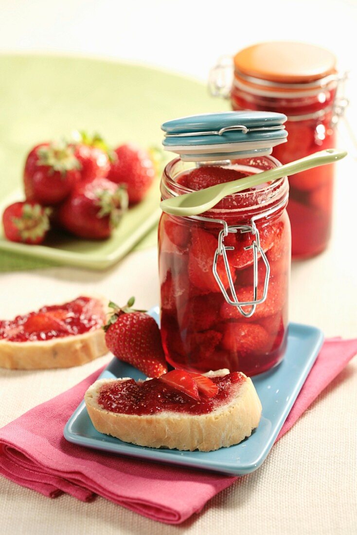 Erdbeermarmelade auf Brot und Erdbeeren in Einmachgläsern