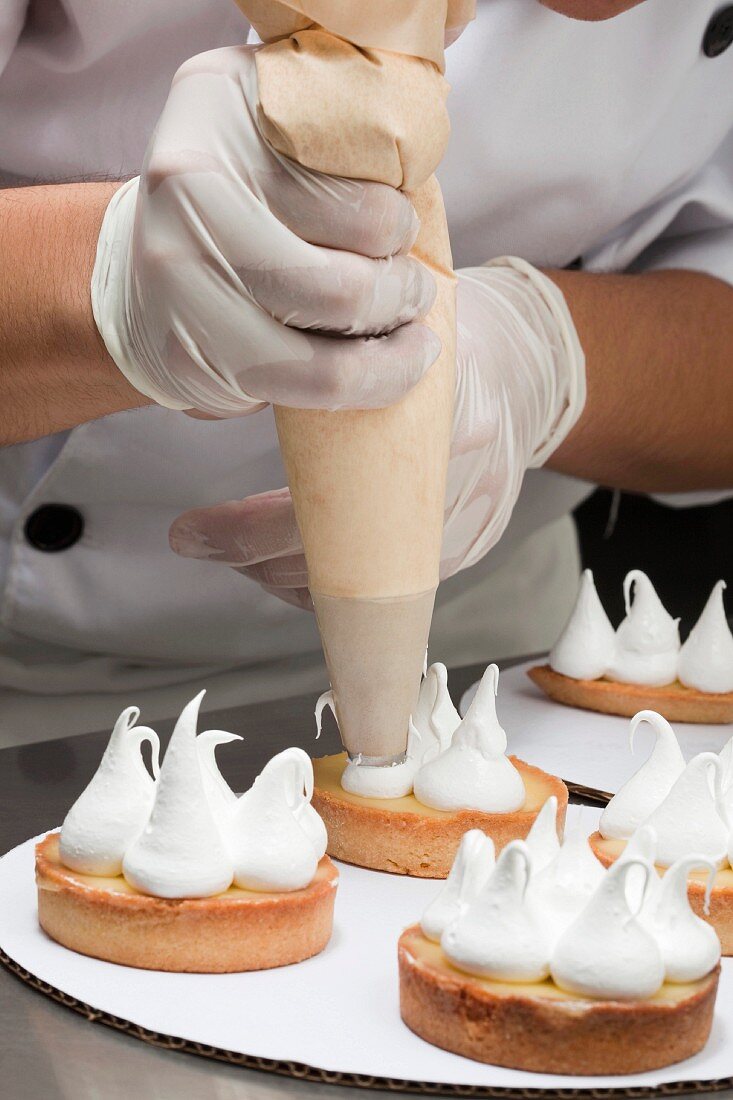 Cook topping the tartlets with meringue