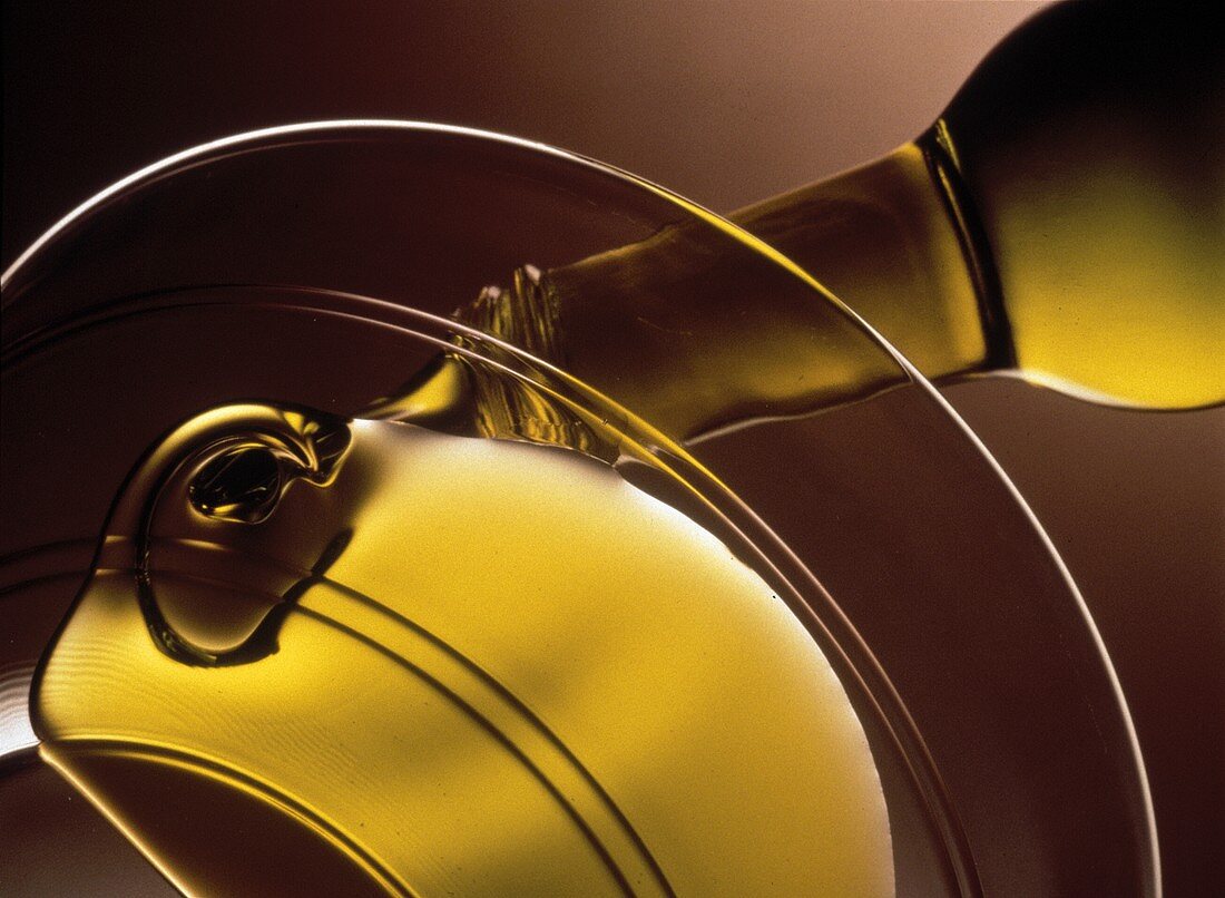 Olivenöl aus Flasche in Glasschale gießen