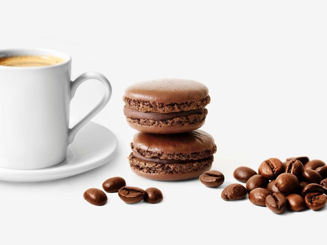 Schokoladen-Macarons, Tasse Kaffee und Kaffeebohnen