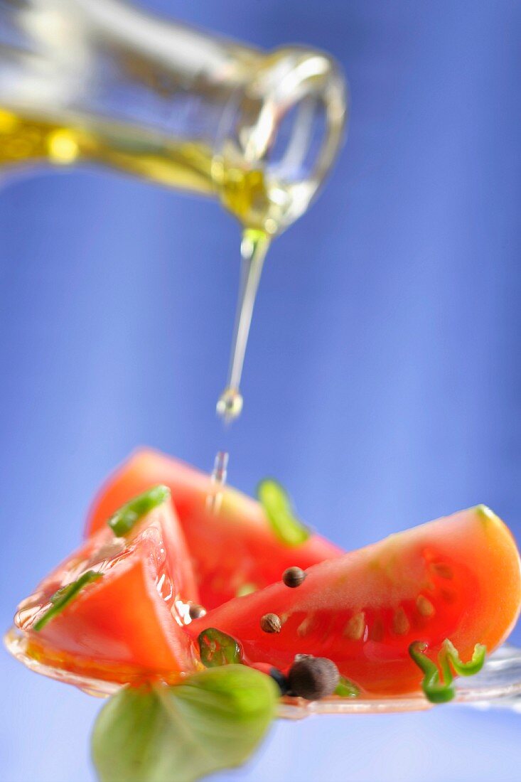 Pouring olive oil onto sliced tomatoes