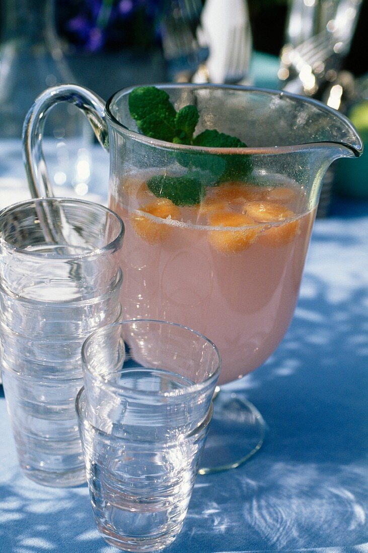 Wassermelonen-Limonade in Glaskanne mit Gläsern im Freien