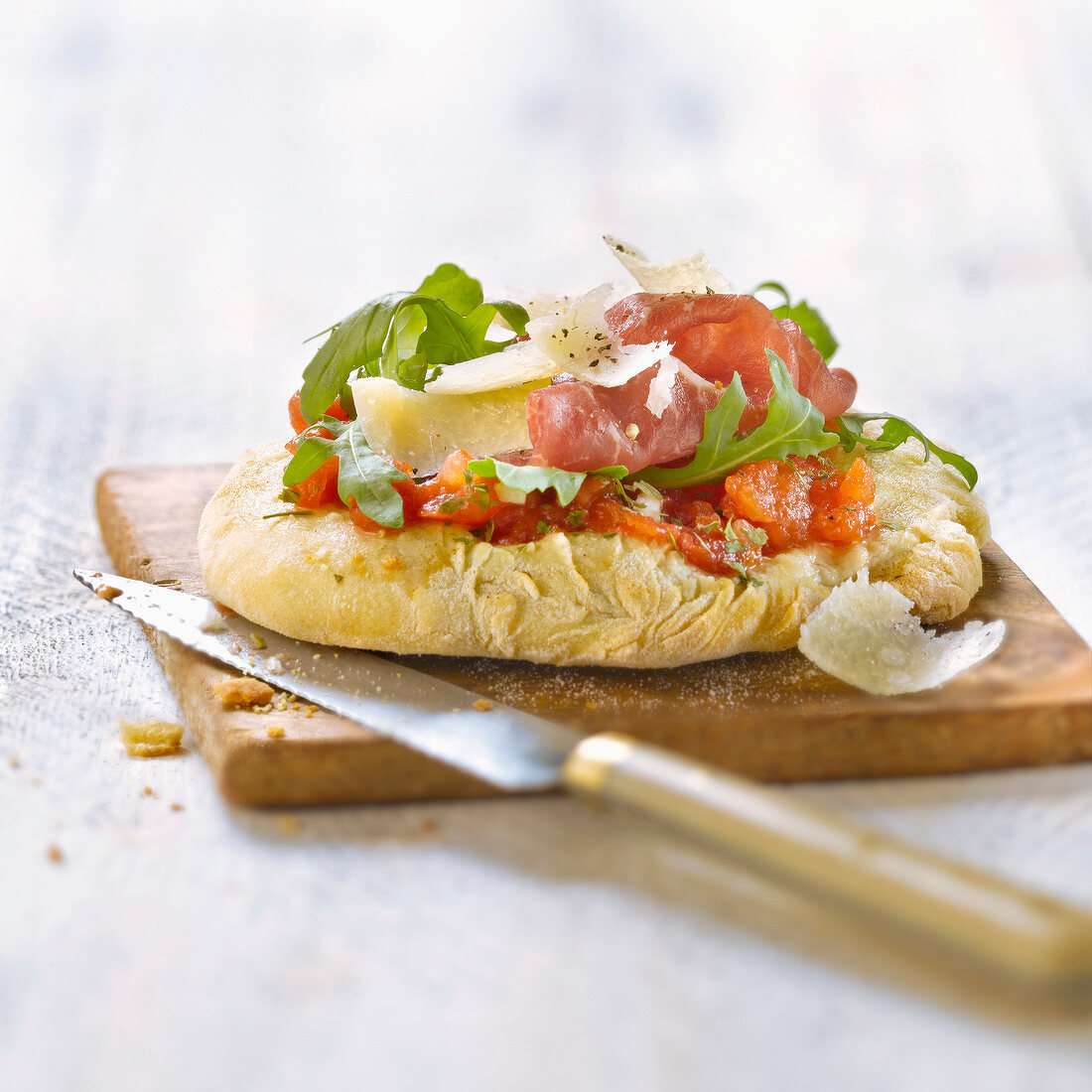 Mini pizza with bresaola, rocket and parmesan cheese