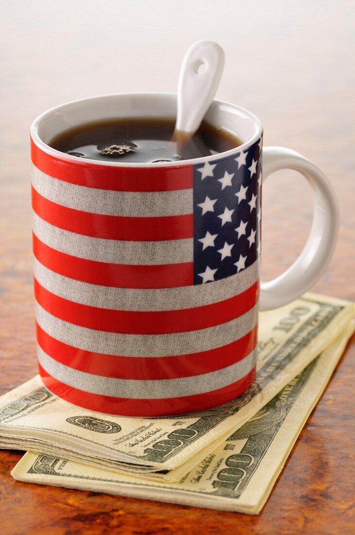 Cup of coffee in a mug with the American flag on it and dollar bills