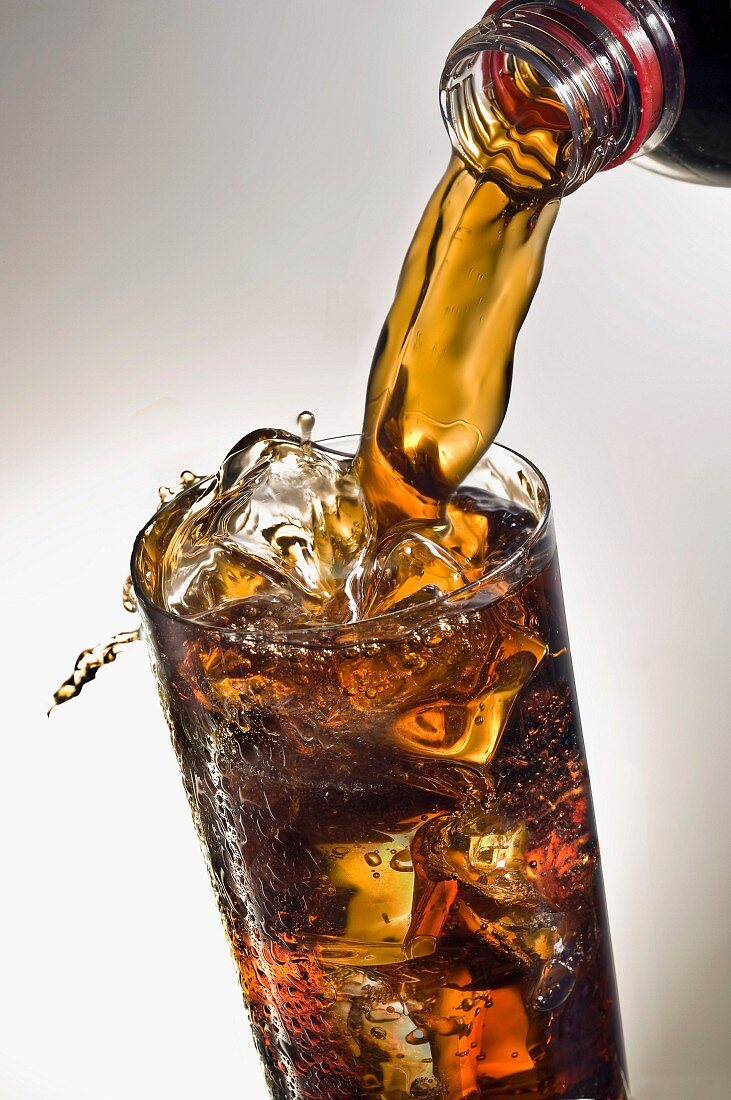 Pouring a glass of Coca-cola with ice cubes