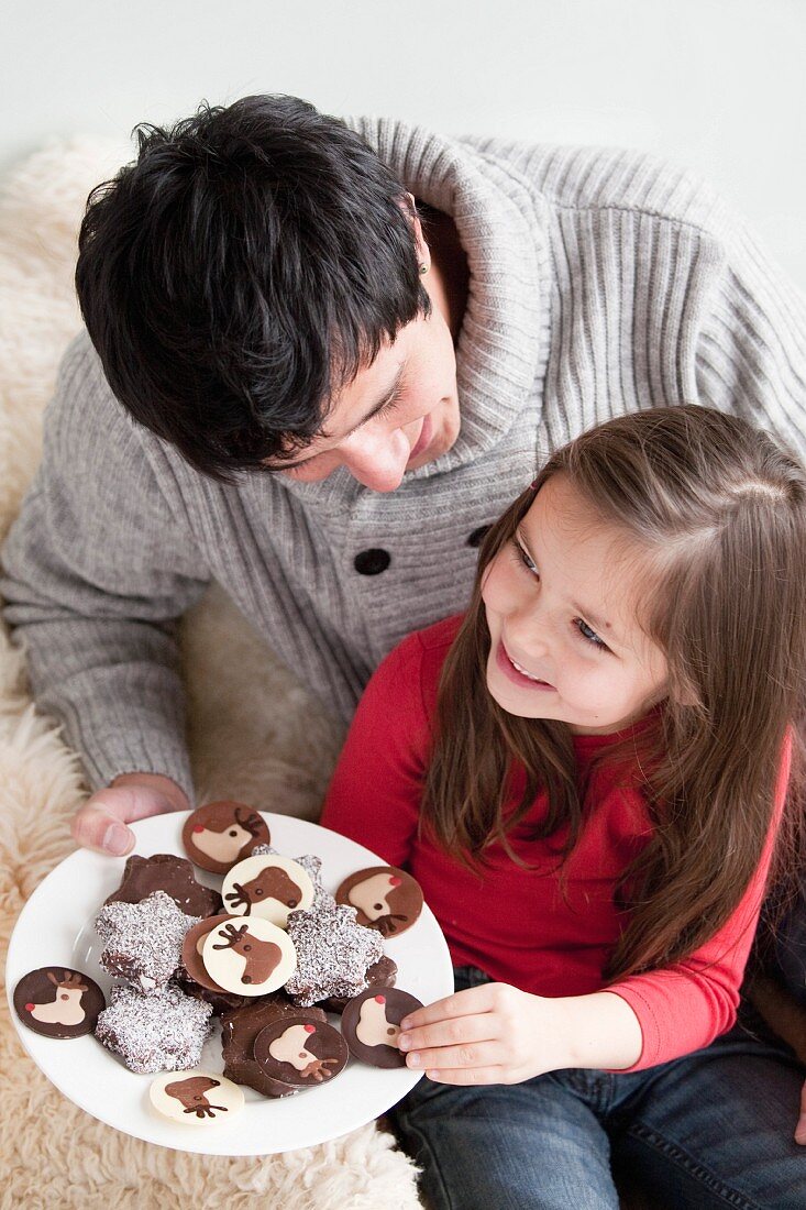 Man offering a plate of chocolate cookies to a young girl