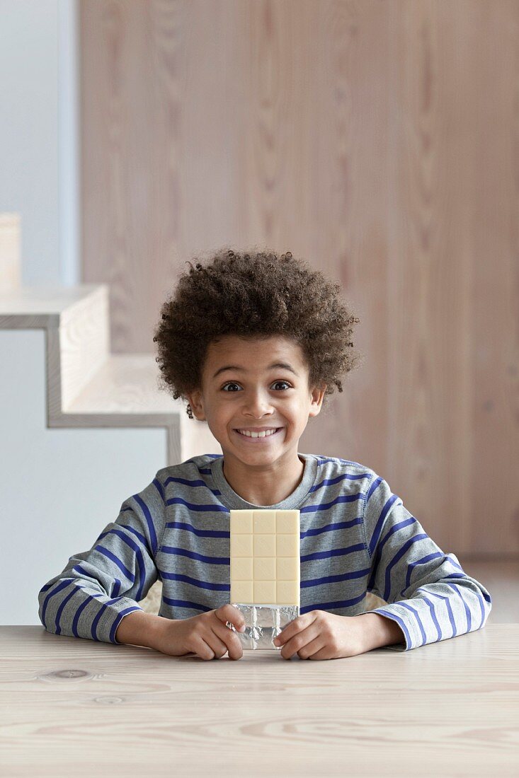 Boy smiling infront of a bar of white chocolate