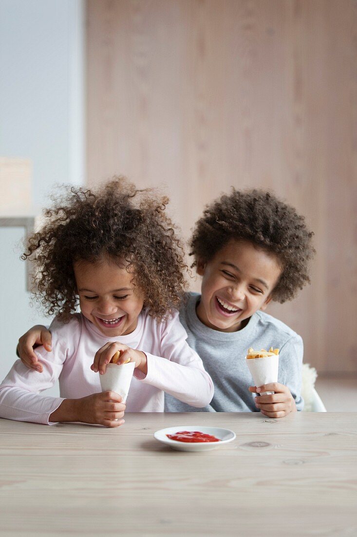 Junge und Mädchen essen Tüte Pommes mit Ketchup
